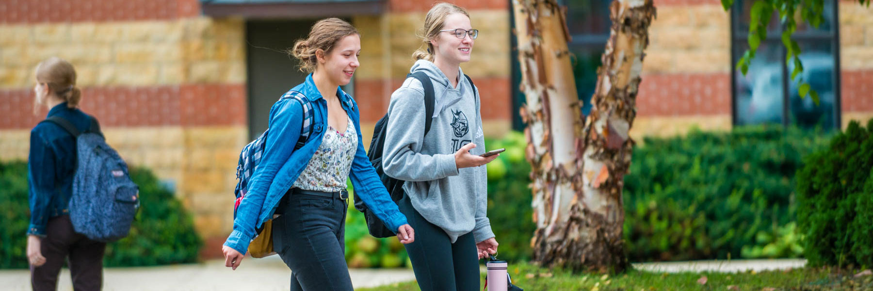 two female students talk outside while walking