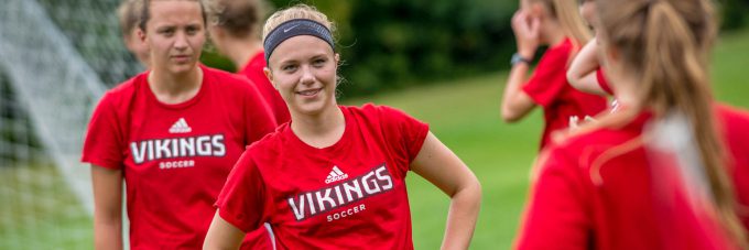 female soccer player listens to another player while at practice