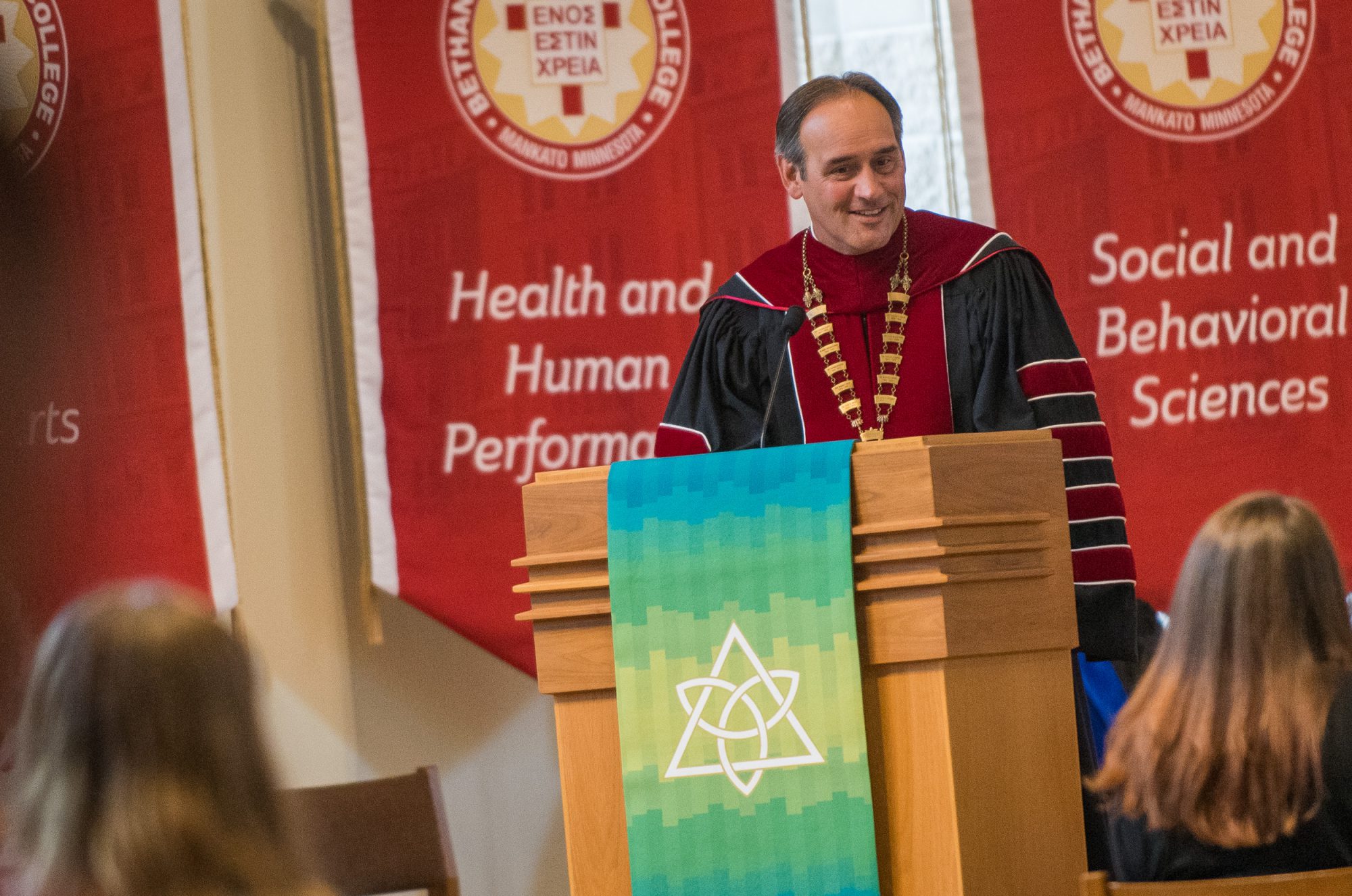 Bethany President Gene Pfeifer smiles and talks at a podium in Trinity chapel.