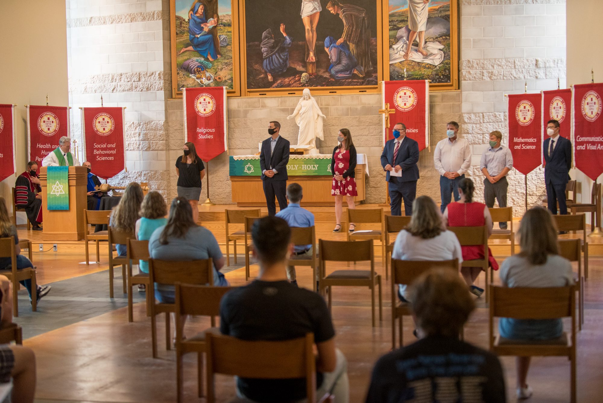 Chaplain Don Moldstad talks to new faculty and staff standing in the front of trinity chapel.