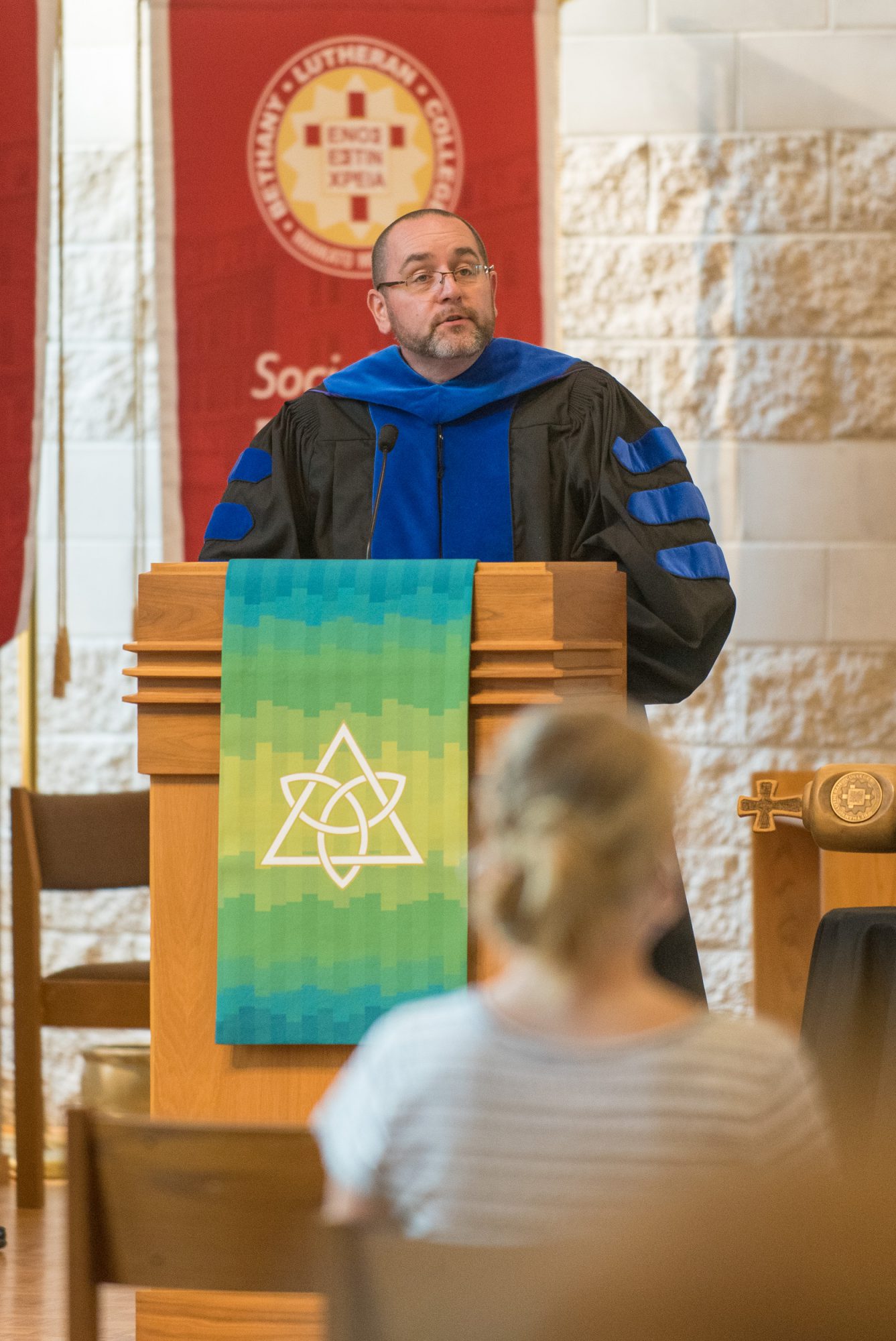 Dr. Jason Lowrey talks behind a podium in trinity chapel