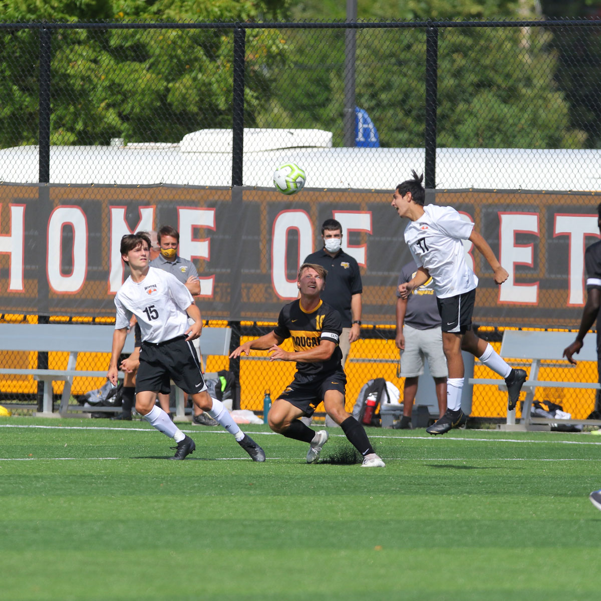 Mankato East boy's soccer player along with 2 opponents, playing soccer on the artificial turf field at Bethany