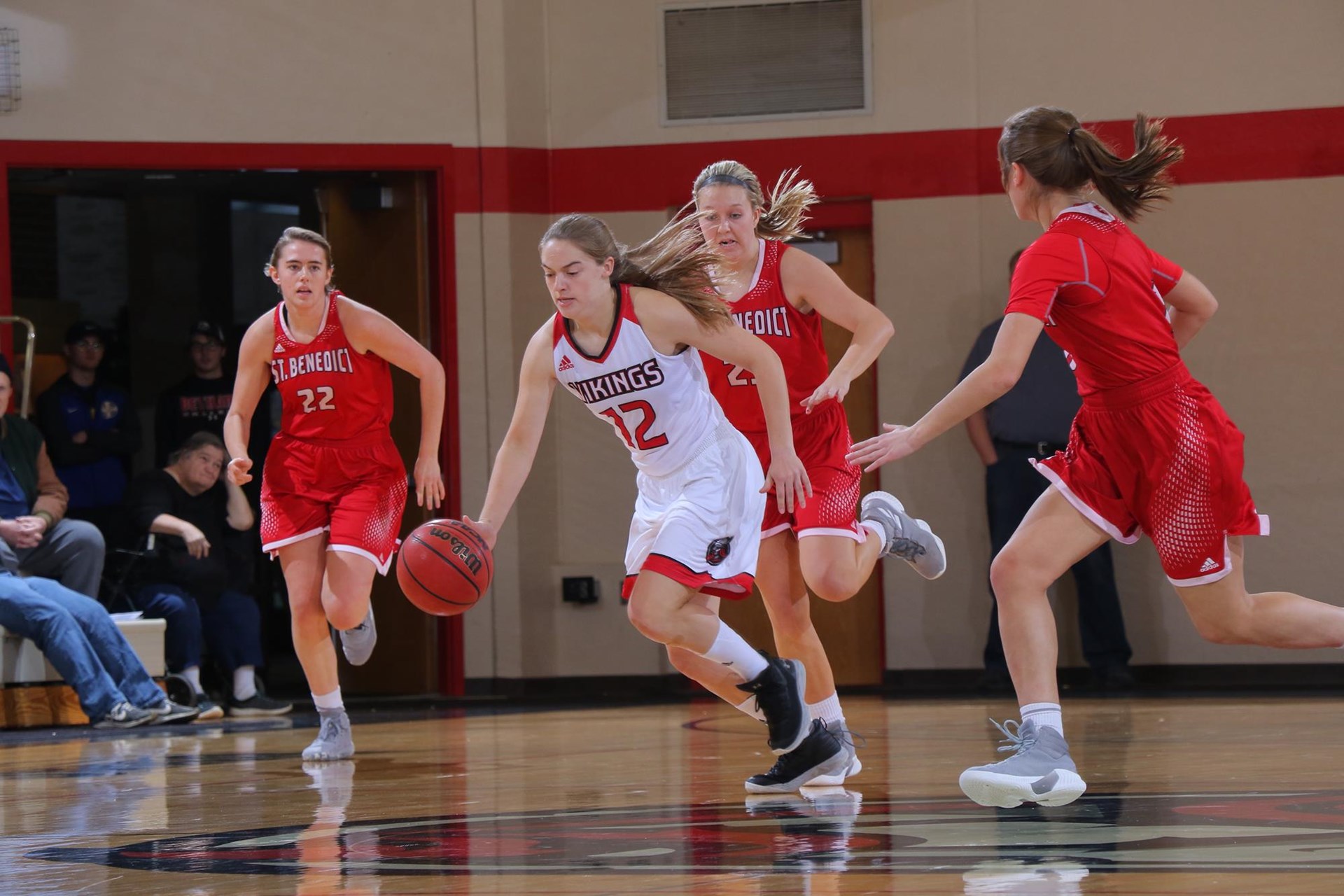 Bethany women's basketball player (#12) dribbles ball away from 3 defenders