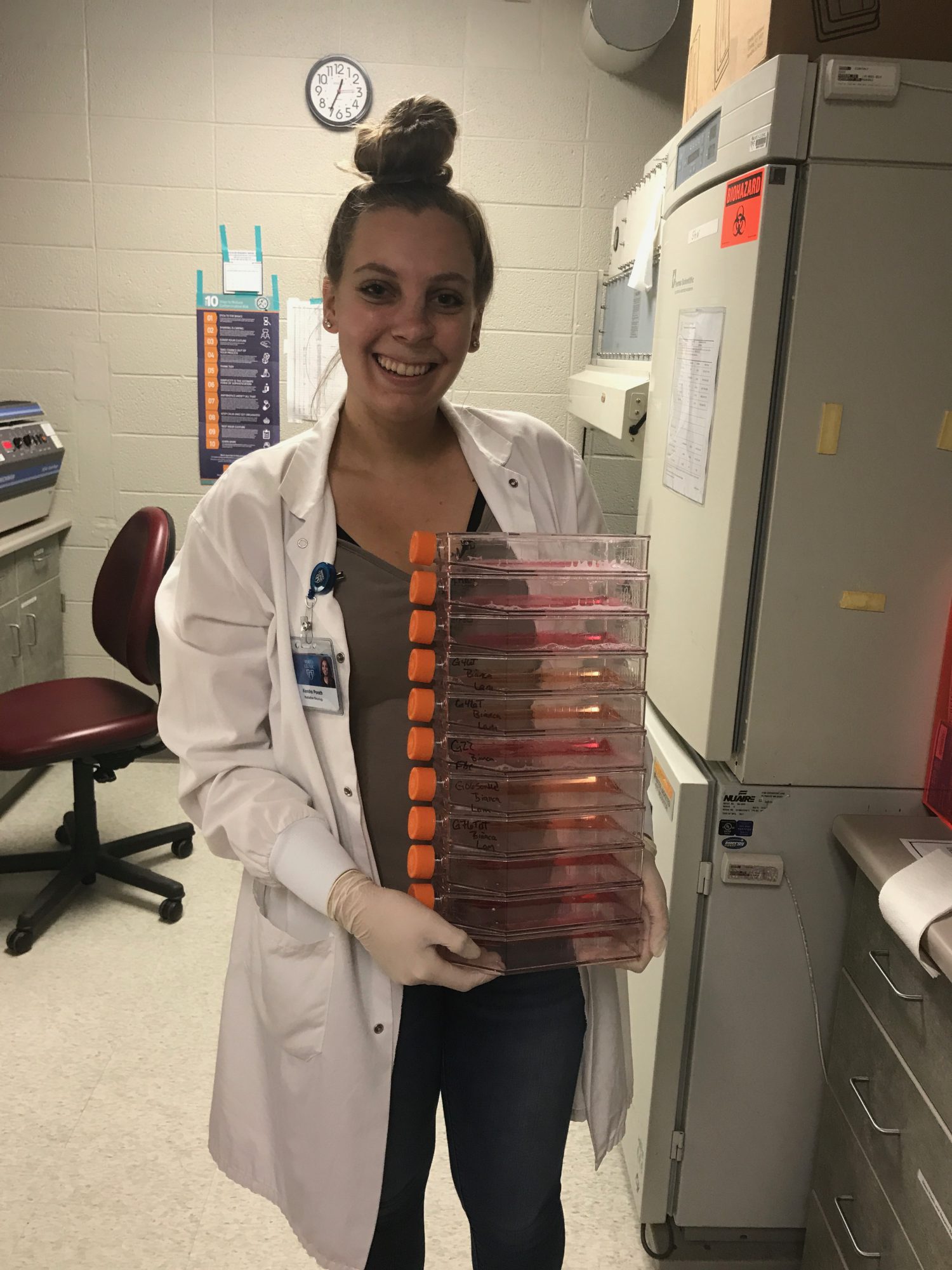 Female carrying a stack of samples to be tested in a medical lab