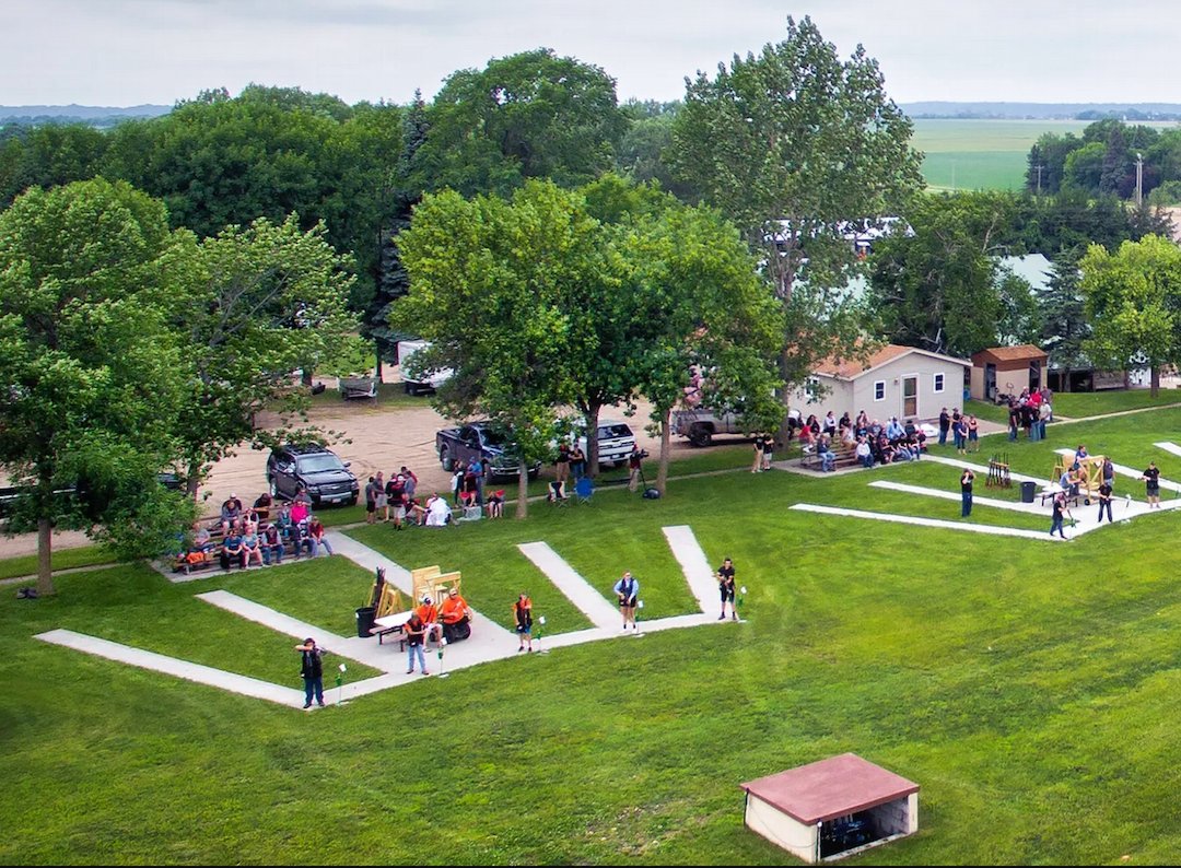 Aerial photo of the Caribou Gun Club facility during a meet; Shooters at their marks with spectators on bleachers behind them