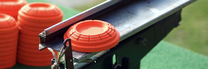 orange clay target on launching station next to stacks of targets