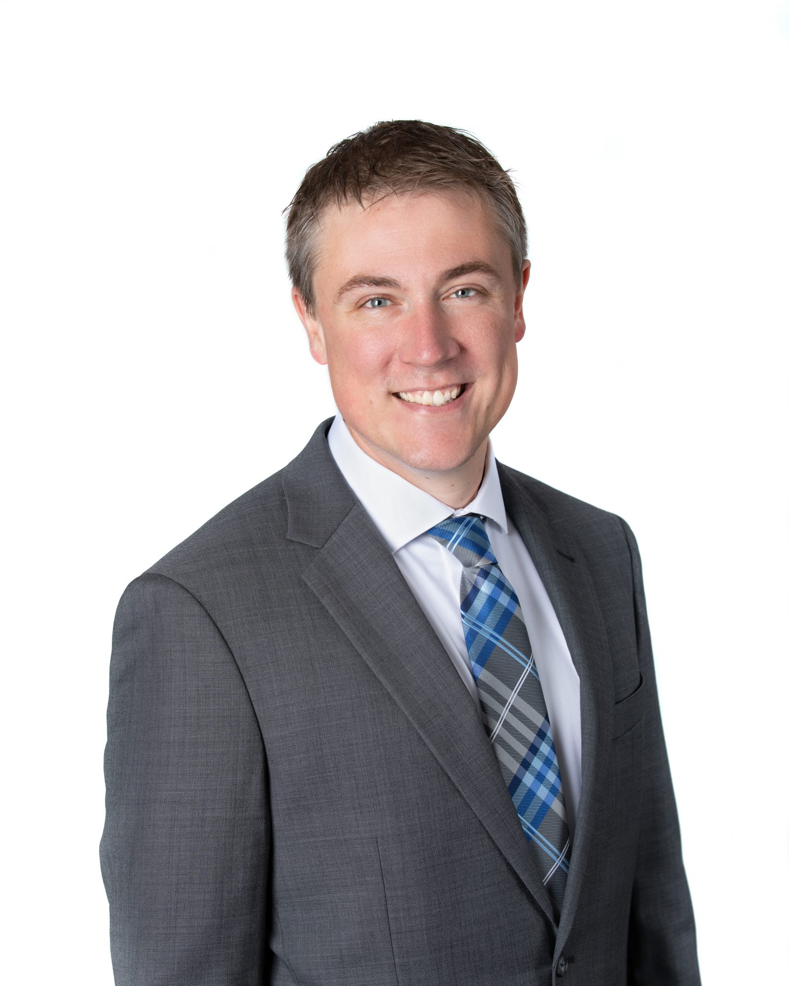 Man in gray suit with white shirt and blue/gray plaid tie