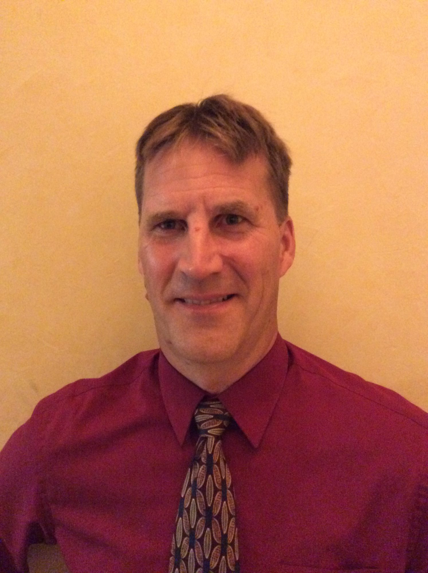 man in red shirt and tie in front of a yellow background