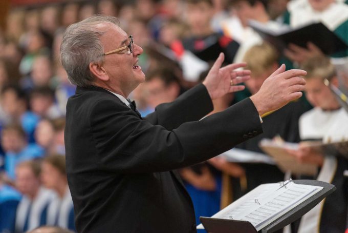 Music director waving arms in front of choir