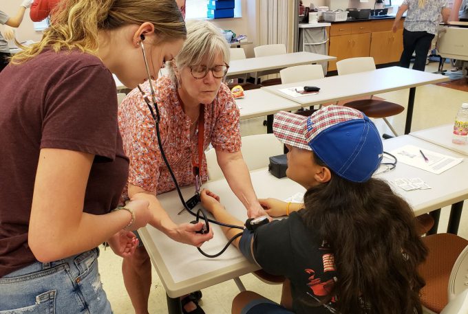 Nursing camp students practice taking blood pressure measurements.