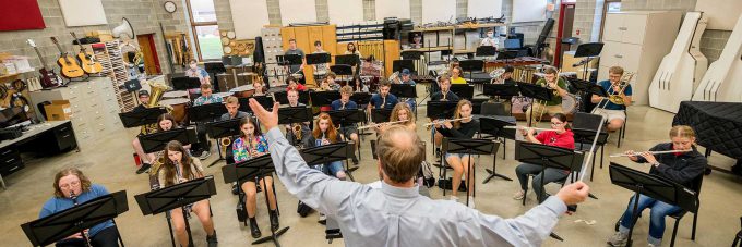 Band students playing instruments led by conductor