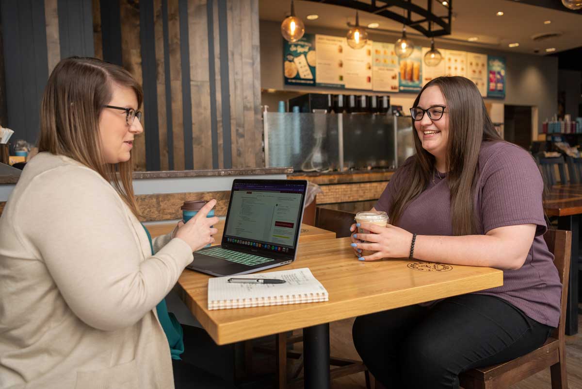 Two girls, Megan Maschoff and Emily Dietz, talking at a table, Bethany Magazine