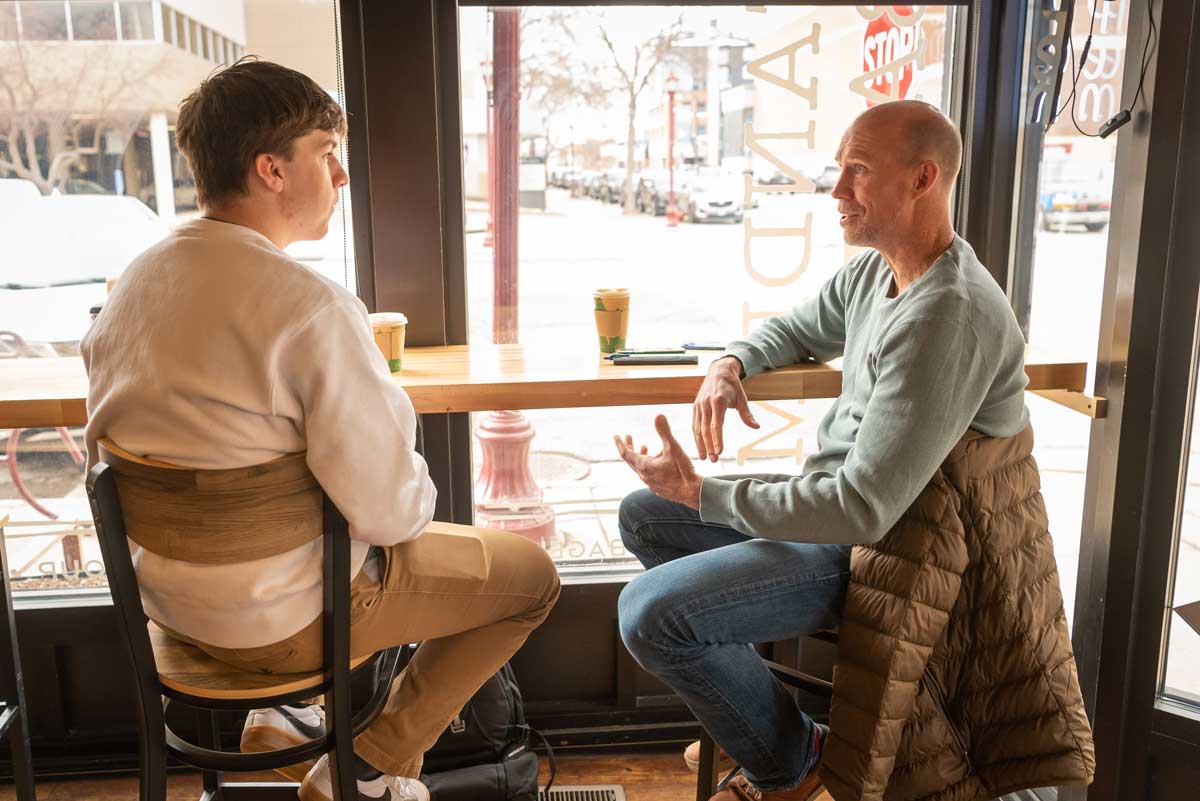 BLC student Aidan Whitcomb and Christopher Harstad talking at a cafe, Bethany Magazine