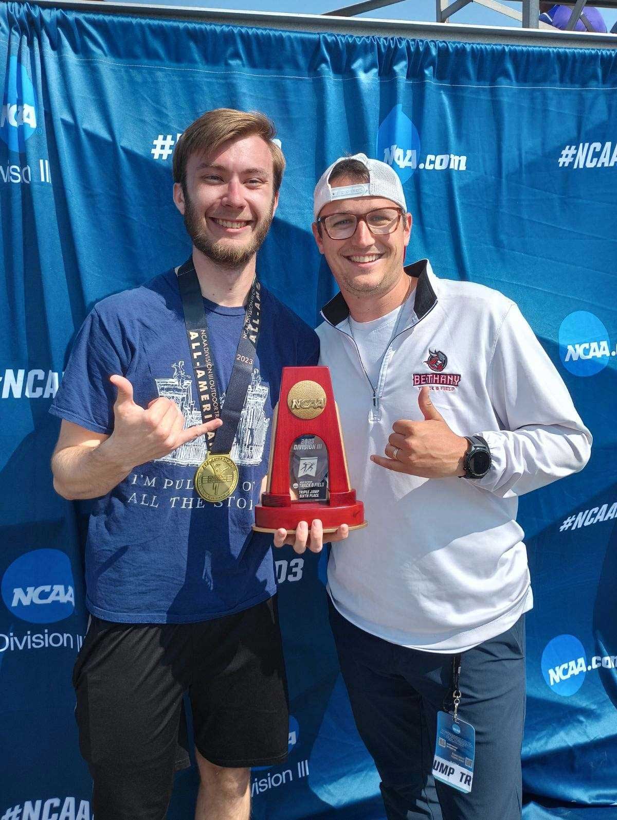 Two guys, Jake Marzinske and coach Michael Dunn, holding a trophy at NCAA DIII National Championships