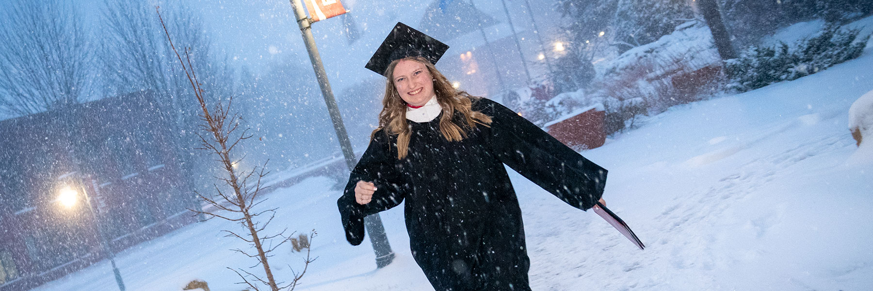 female graduate walking in snow