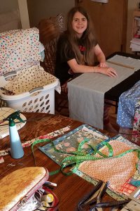 Two of the Kovaciny kids help cut and iron fabric for masks.