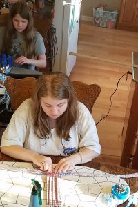 Three of the Kovaciny kids help cut and iron fabric on tables and countertops