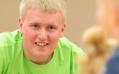 male student in bright green shirt smiles at children